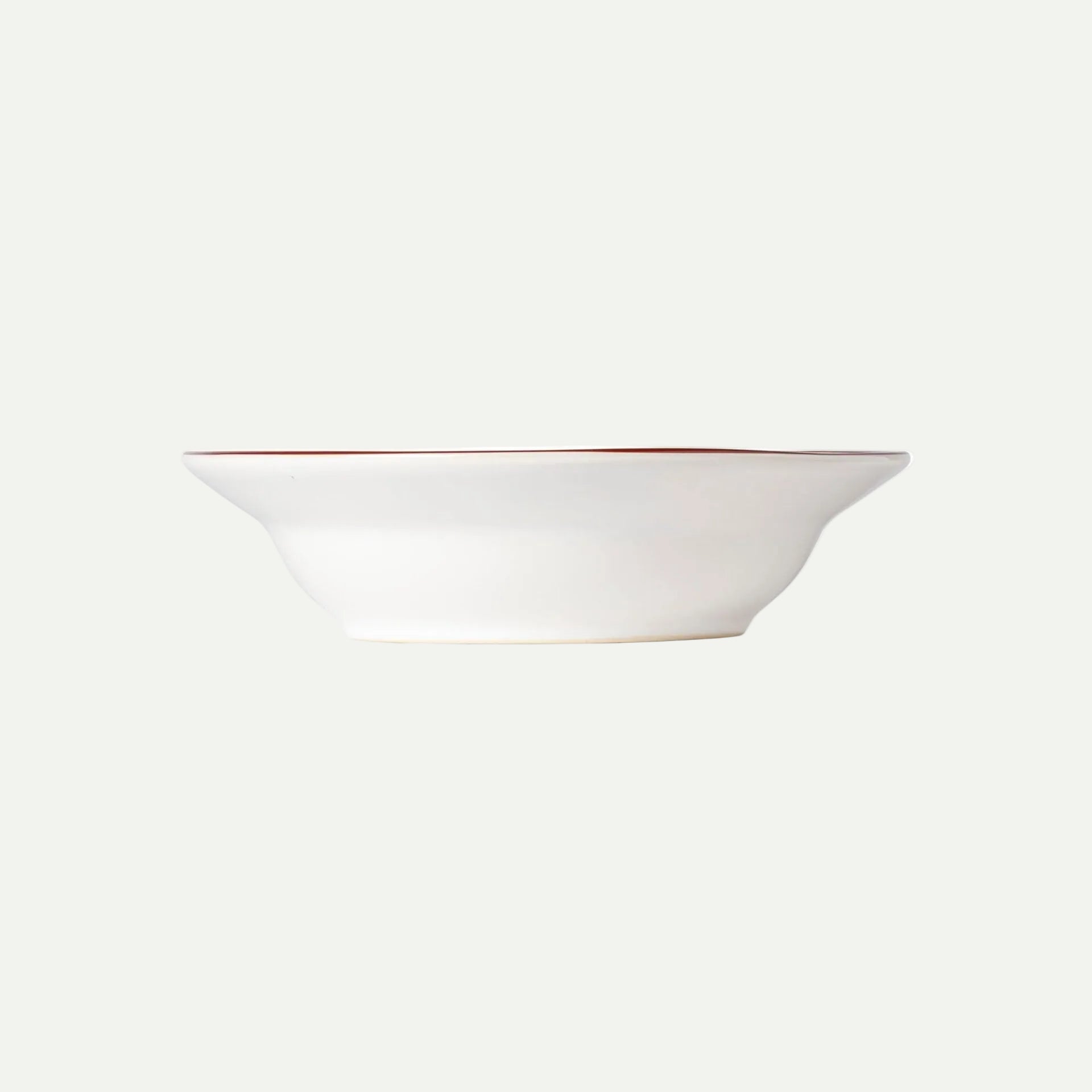 White ceramic bowl with a thin red rim on a white background