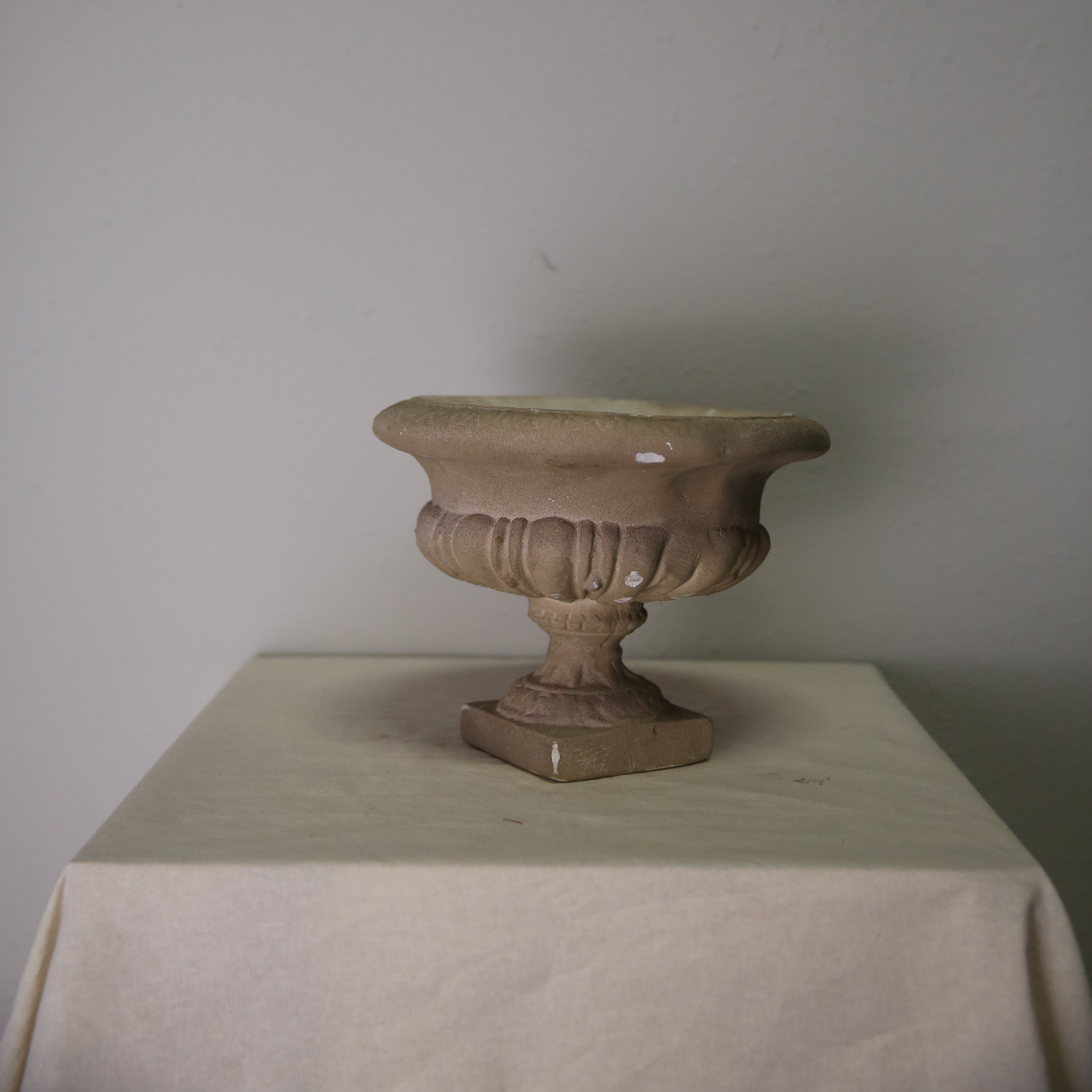 Decorative urn on a white pedestal against a plain background