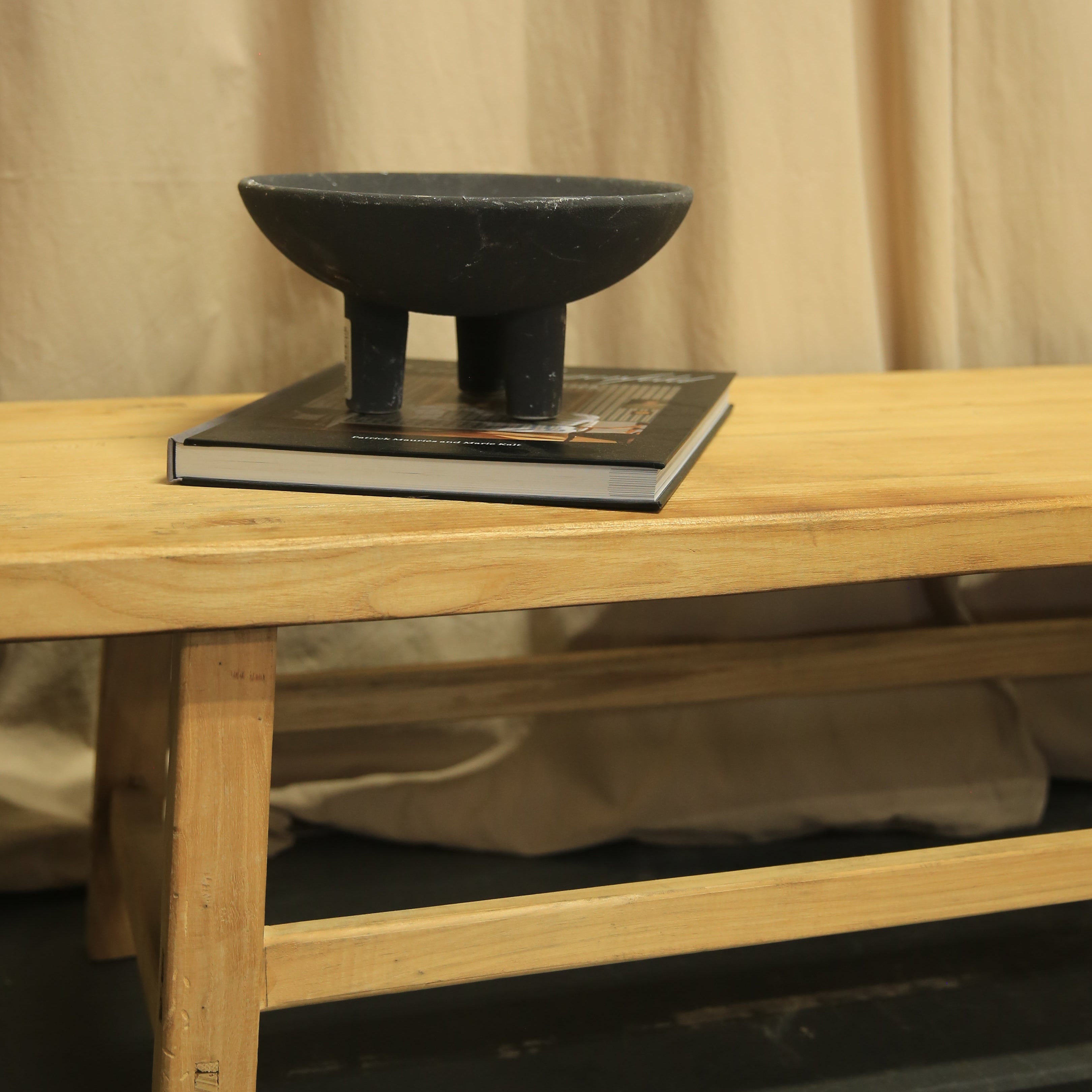 Wooden stool with a metal footrest against a neutral background