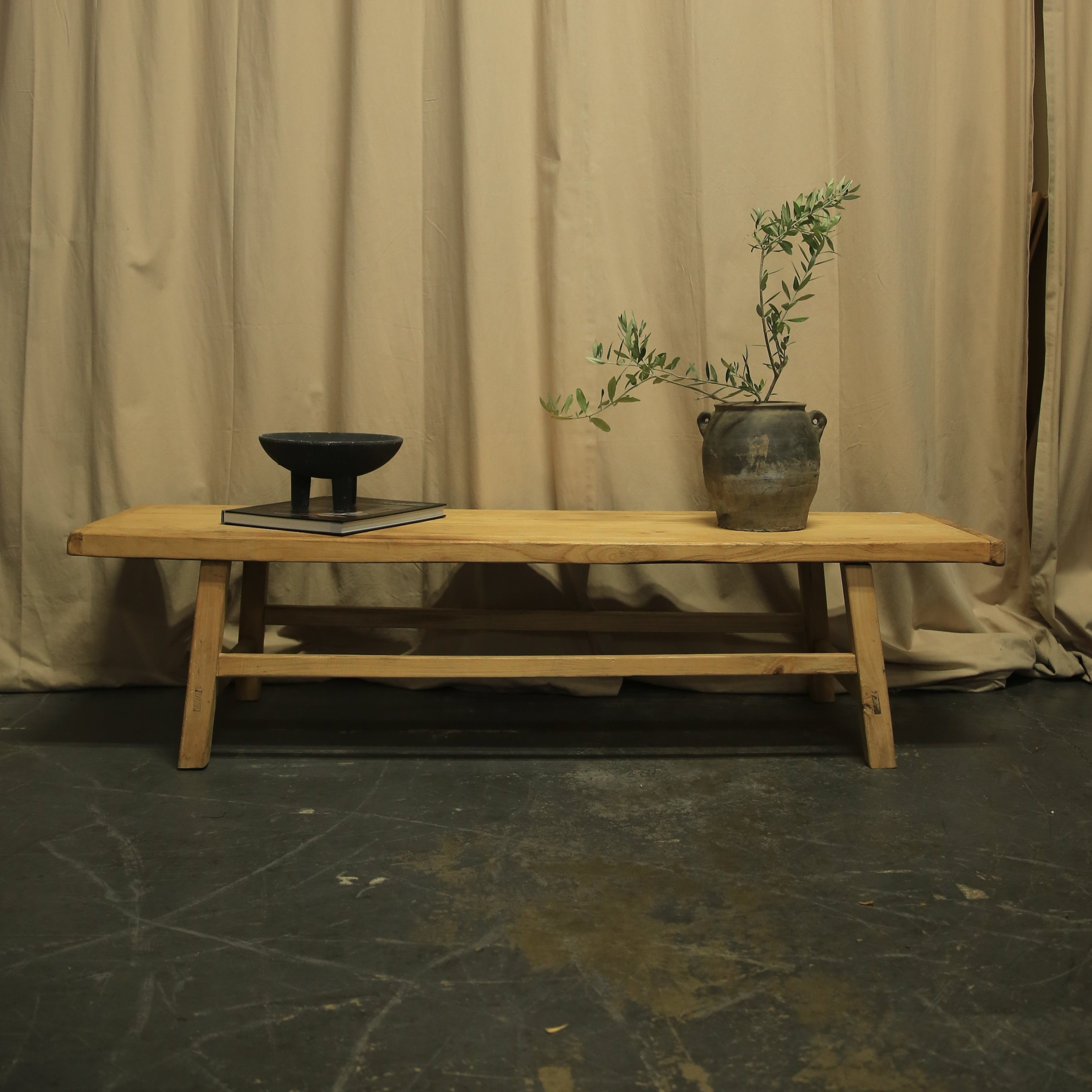 Wooden chair with a plant against a beige curtain backdrop