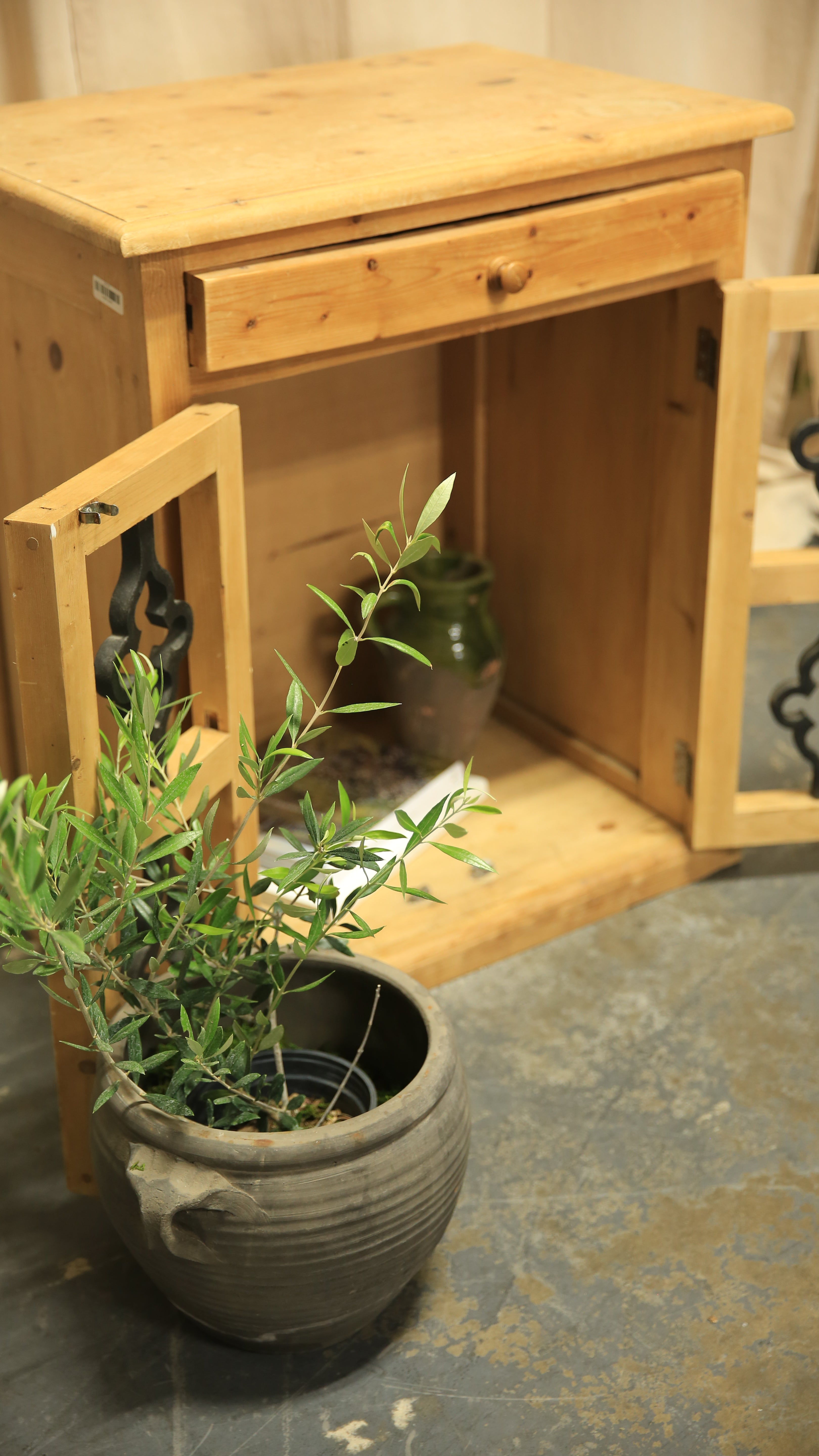 Wooden cabinet with a plant on top against a textured wall.