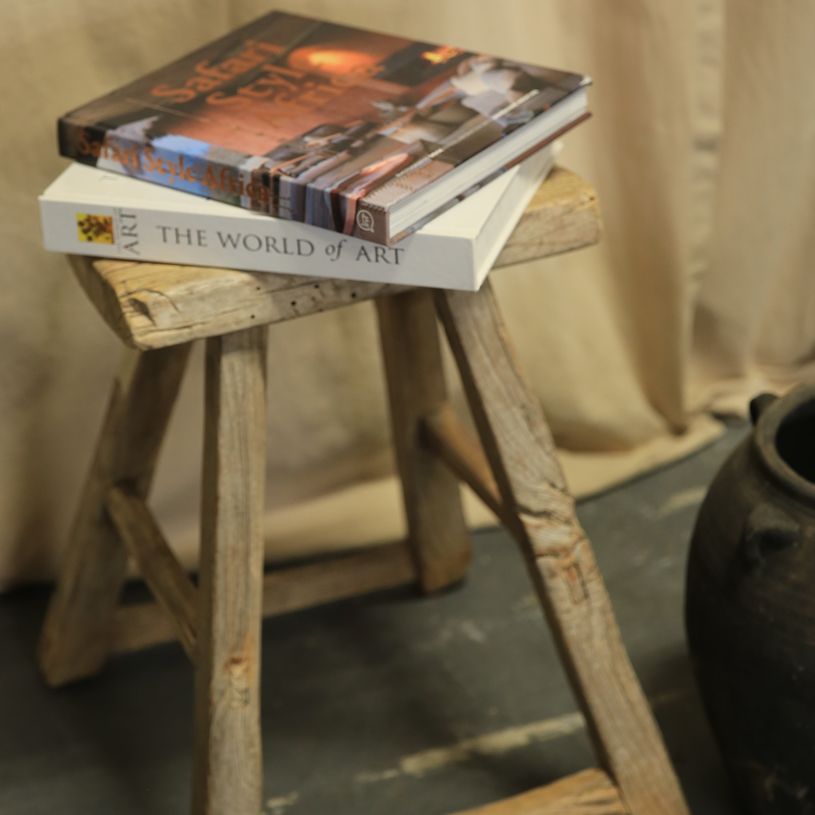 Two books stacked on a wooden stool against a neutral background