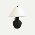 Table lamp with a matte black ceramic base shaped like a vintage amphora and a wide, off-white conical lampshade, set against a plain light background.