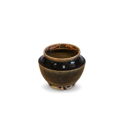 A small round ceramic jar with a glossy dark brown and black glaze, featuring a rustic light brown rim, shown on a plain white background.