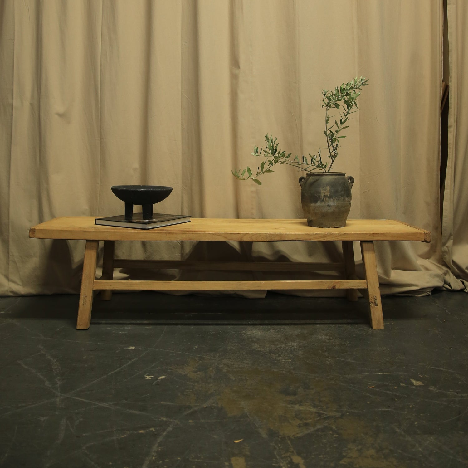 Wooden chair with a plant against a beige curtain backdrop