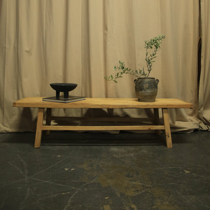 Wooden chair with a plant against a beige curtain backdrop